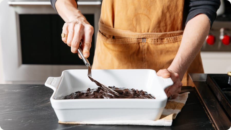 Off-set spatula spreading chocolate in a baking dish