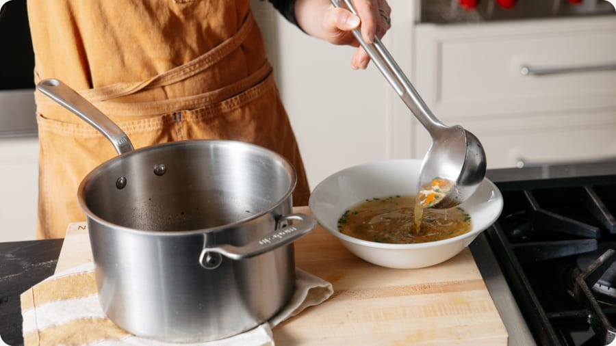 Ladle serving soup from a pot into a bowl