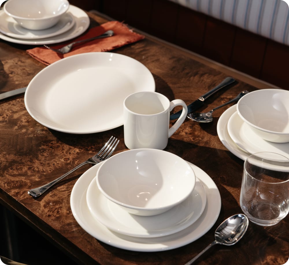 Full tabletop setting with plates, bowls, mug, glass, and flatware