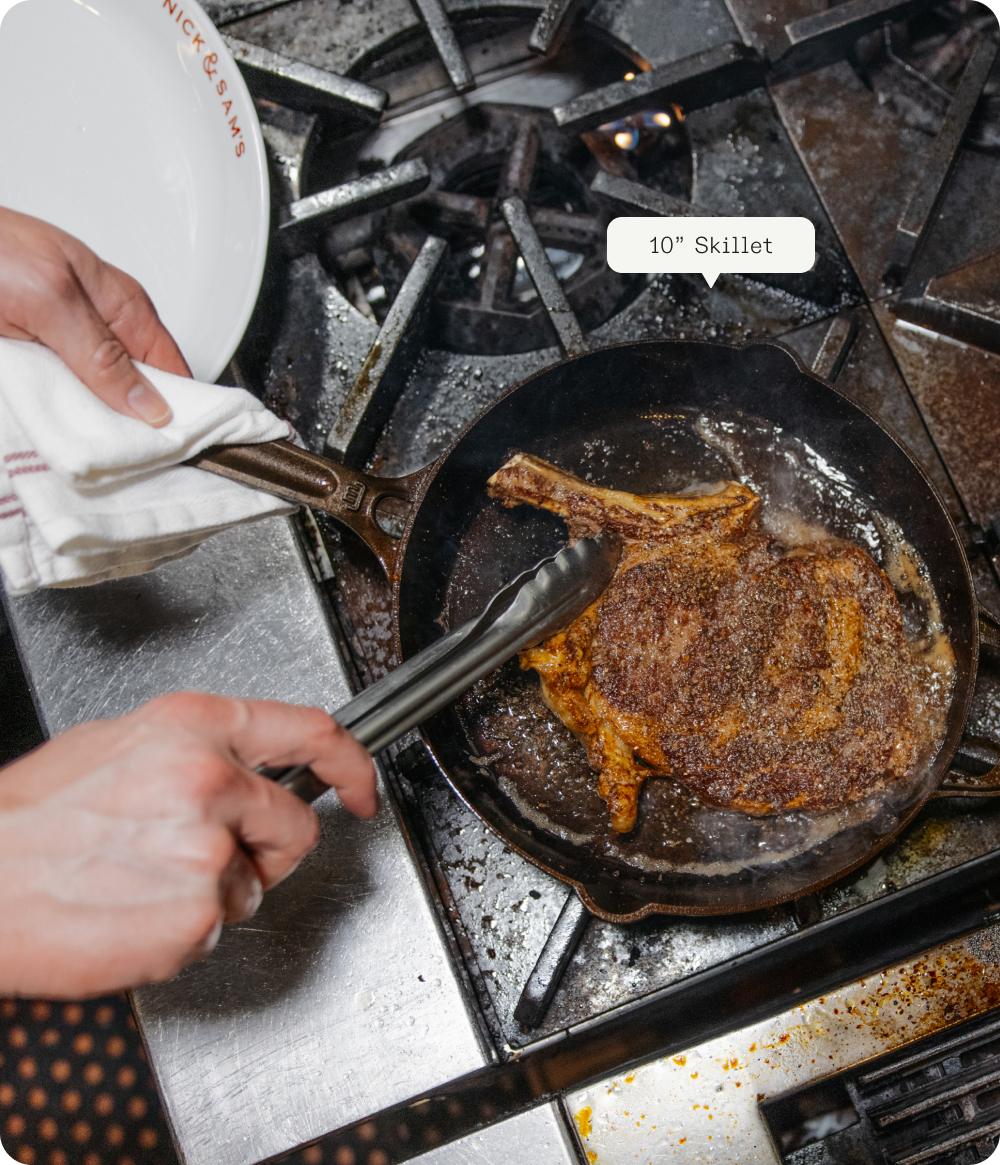 Bone-in steak searing in a 10 inch cast iron skillet on the stove