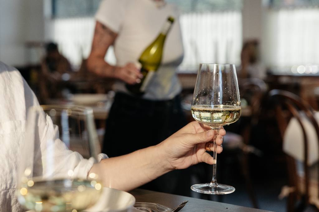 A diner holding a Made In Crystal White Wine Glass by the stem