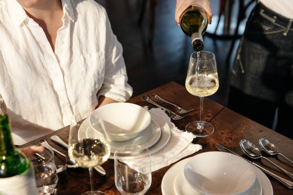 White wine poured at a set table with Made In plateware and flatware
