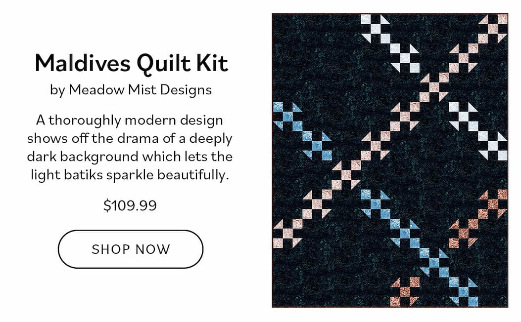 Image: A dark blue quilt with light tan and light blue crossing lines. Text: 