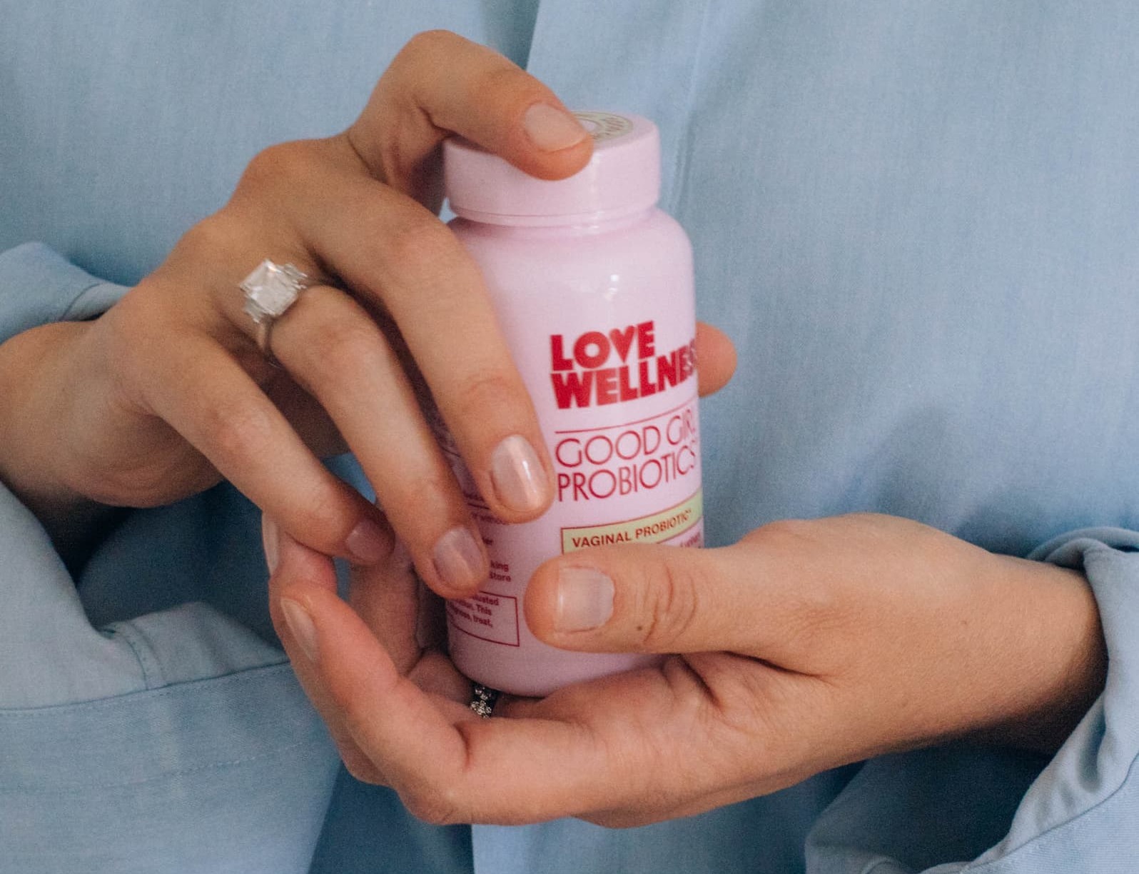 Photo of woman's hands holding on to a pink bottle of Good Girl Probiotics, one of Love Wellness' top selling products.
