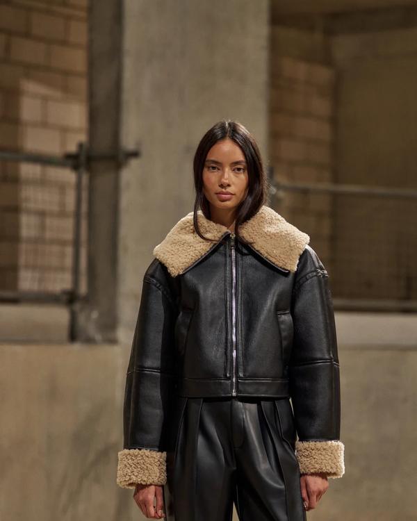Model in a black faux leather aviator jacket with shearling collar