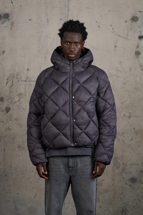 Model in a charcoal diamond-quilted reversible puffer coat