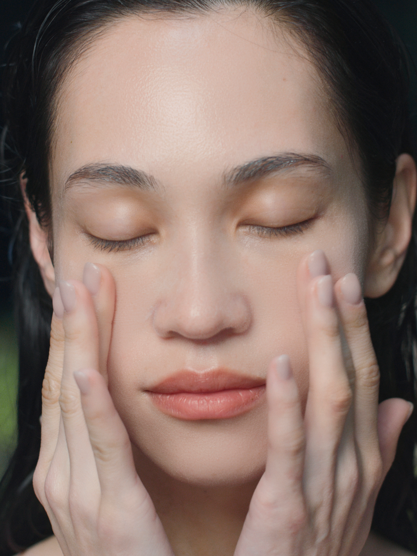 An image of a model applying Tatcha skincare on her face