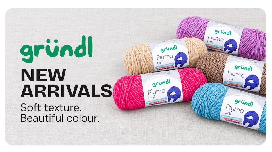 Five Gründl Piuma Uni yarn balls in pink, purple, blue, beige and mocca, arranged on a light linen background.