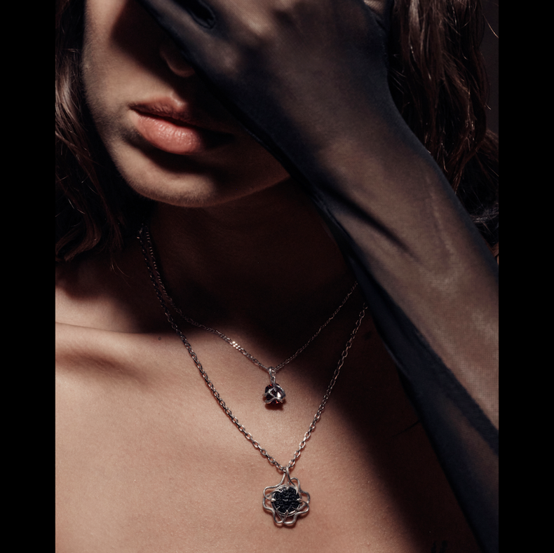 A model wearing the Medusa cameo pendant layered with a skull charm necklace
