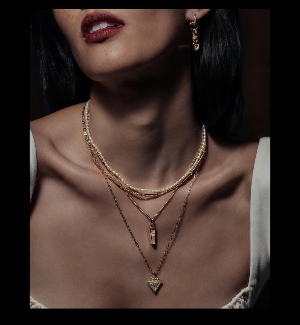 Model wearing the Abracadabra Filigree Pendant layered with gold necklaces