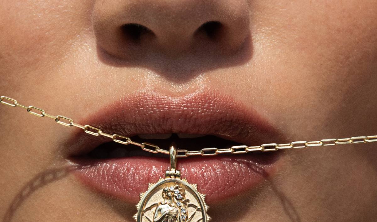 Model holding a 14k gold Goddess pendant with diamonds between her lips