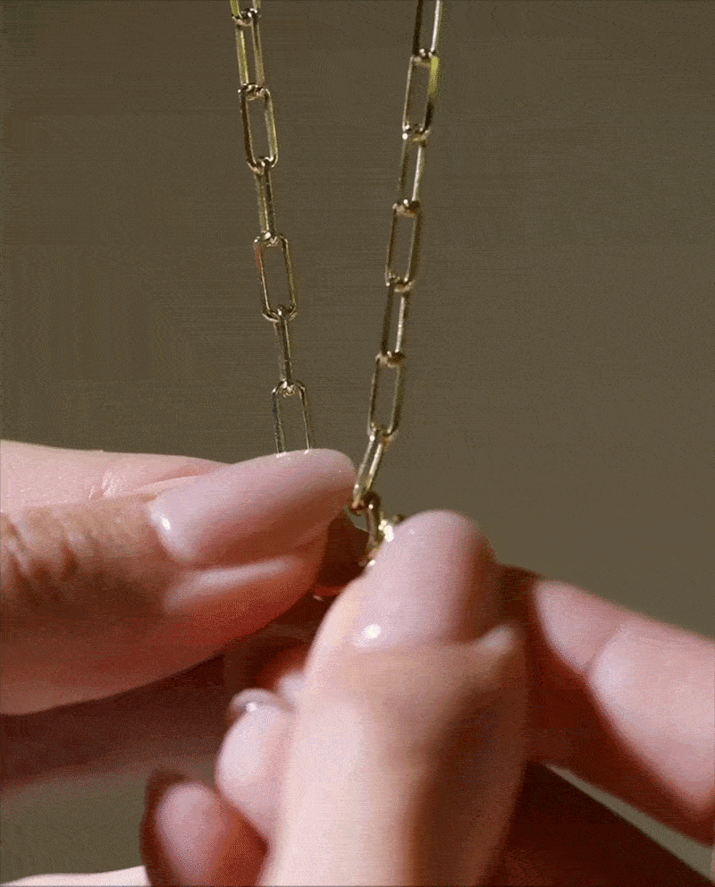 Hands clipping a charm onto a Collector chain