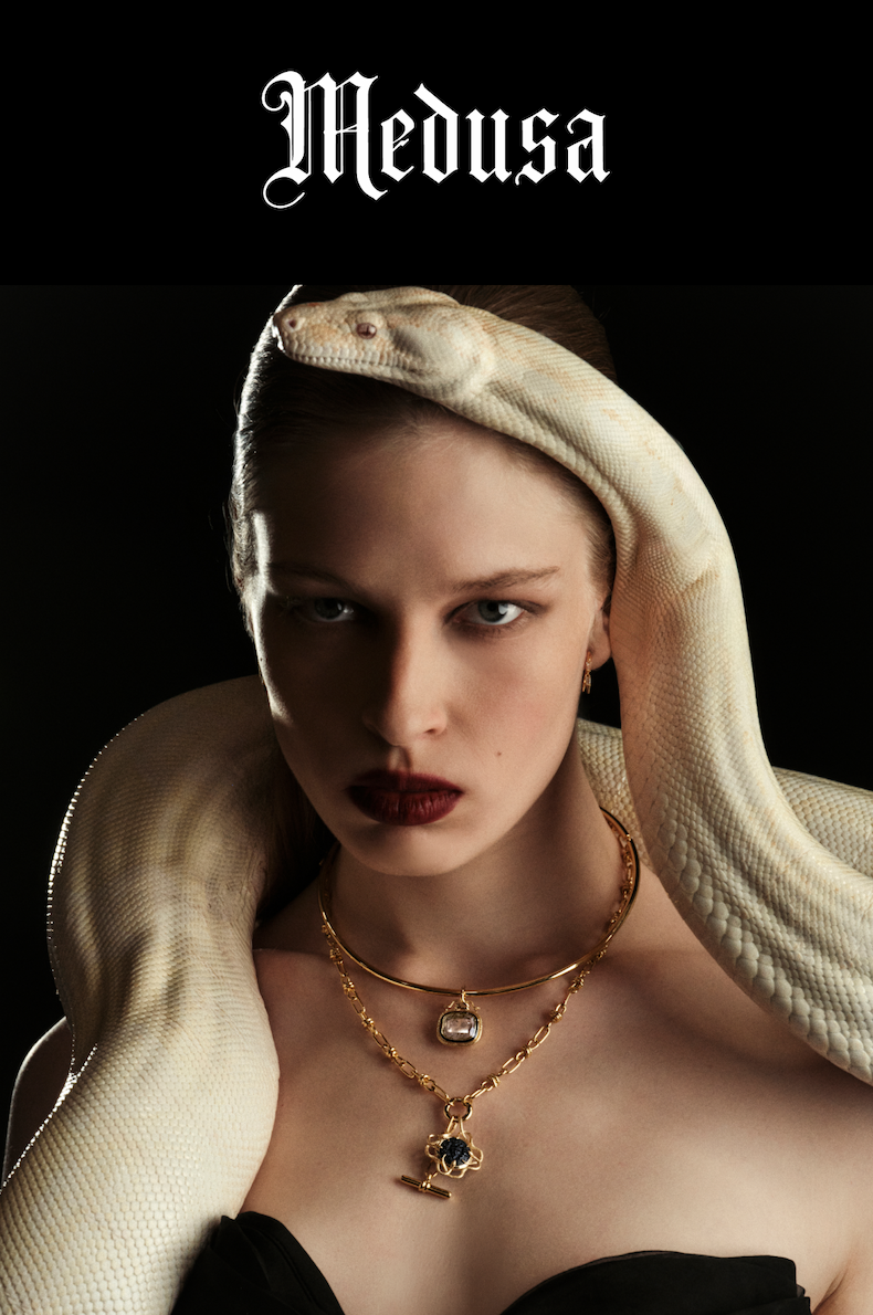 A model in gold Medusa jewelry with a white snake draped over her head and shoulders