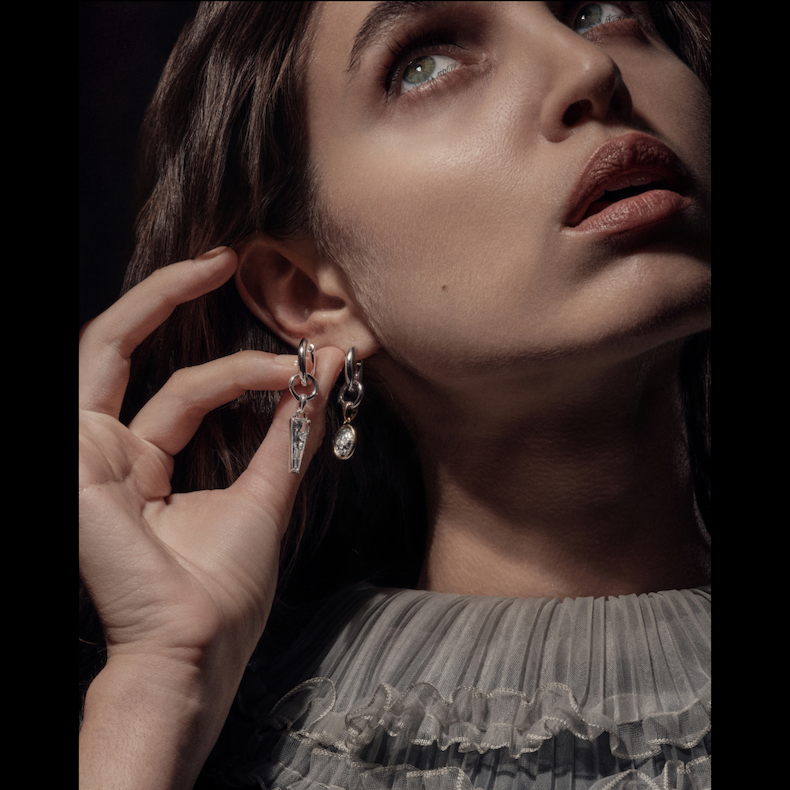 A woman wearing skull and coffin charm earrings