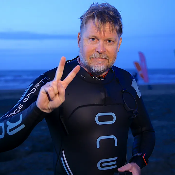 Karl Bushby wears wetsuit. Peace sign with hand.