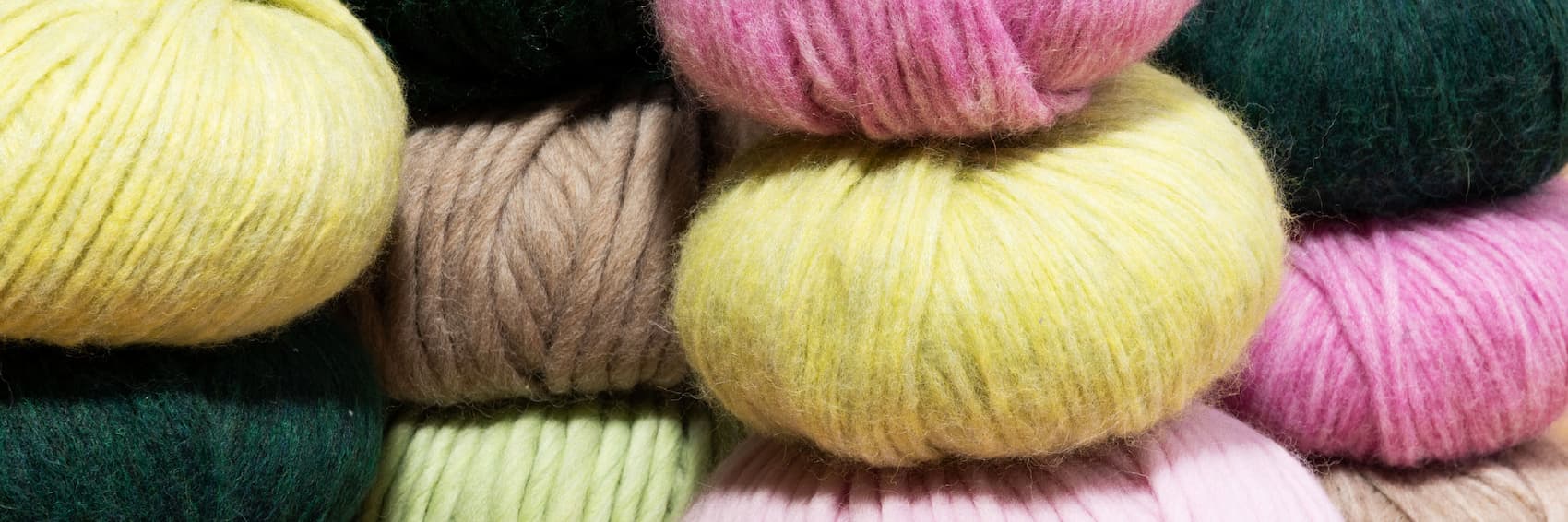 various bulky yarns in greens, yellows, and pink. >>