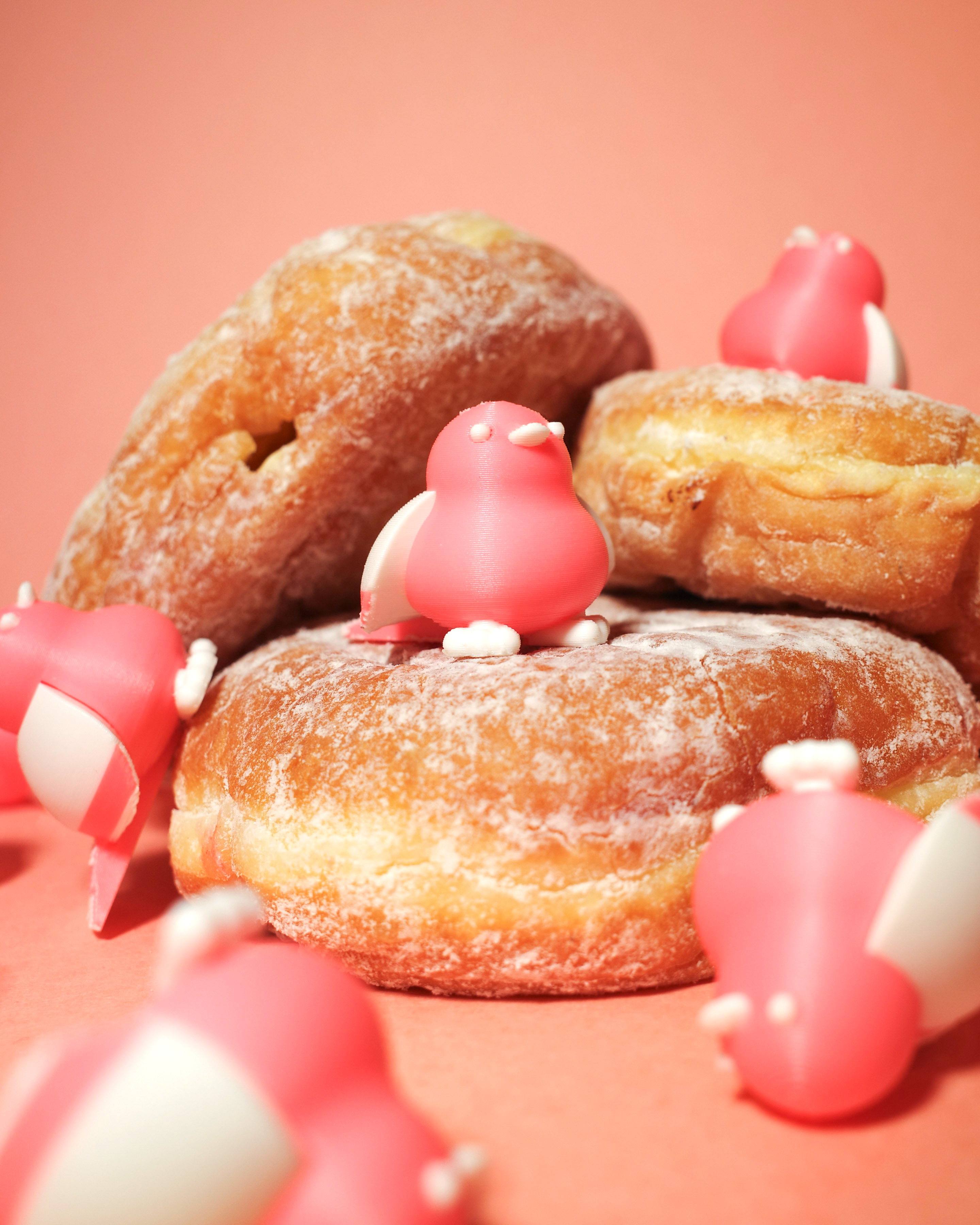 Small pink birds perched on powdered jelly donuts.