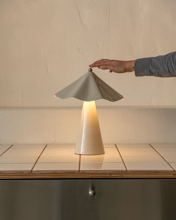 A hand tapping the top of a glowing Sand Robyn lamp