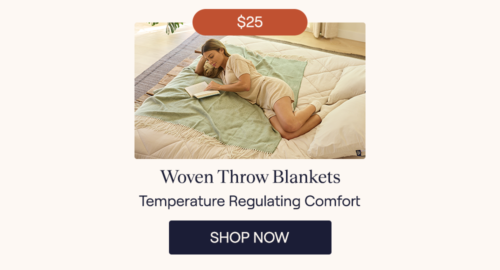 A woman reading in bed while laying on the Juniper Woven Throw blanket