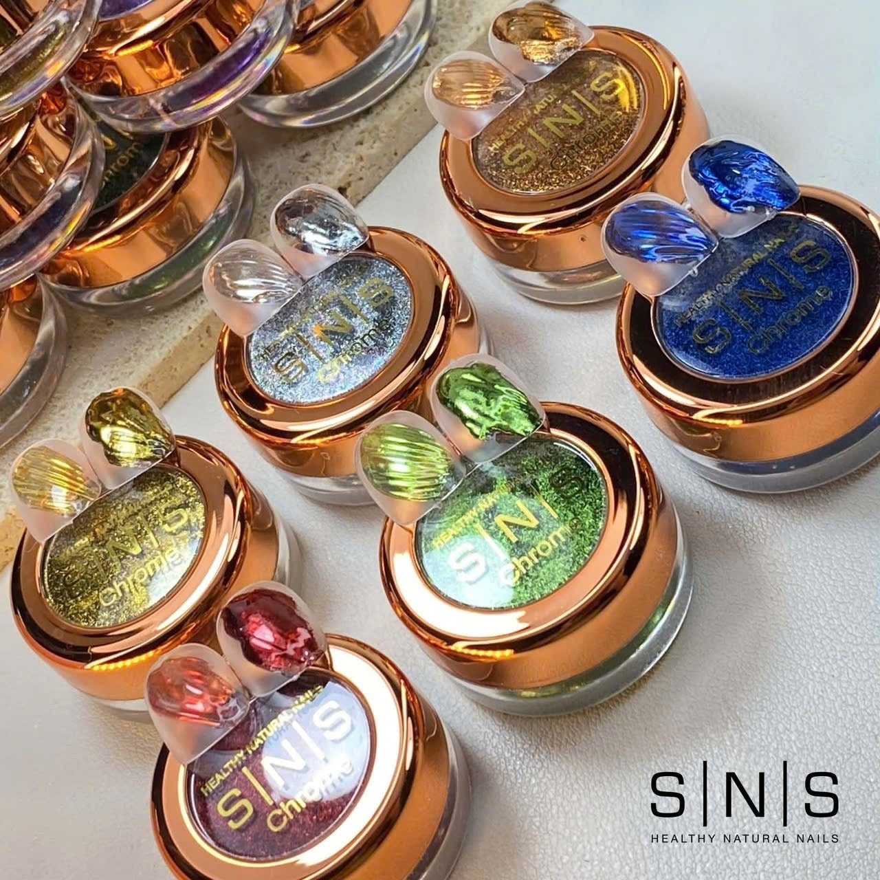 SNS Chrome powder jars with rose gold lids and swatch tips in silver, gold, blue, green and red