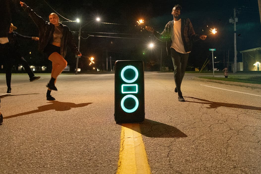 people dancing in street around Klipsch party speaker