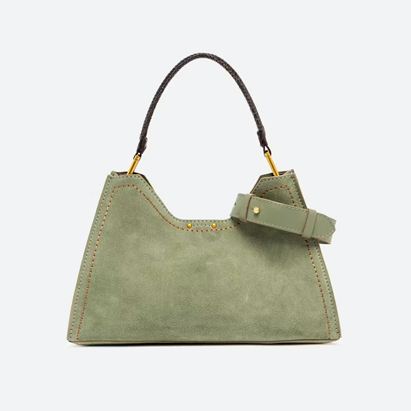 Sage green suede handbag with contrast stitching, a braided dark handle, gold-tone hardware, and a decorative leather strap detail. Fearrington Village.