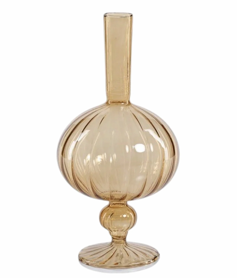 Amber glass bud vase with a rounded ribbed body, slender neck, and decorative pedestal base. Fearrington Village.