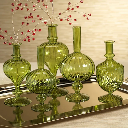 Collection of five sculptural green glass bud vases arranged on a mirrored tray with red crystal-beaded branches. Fearrington Village.
