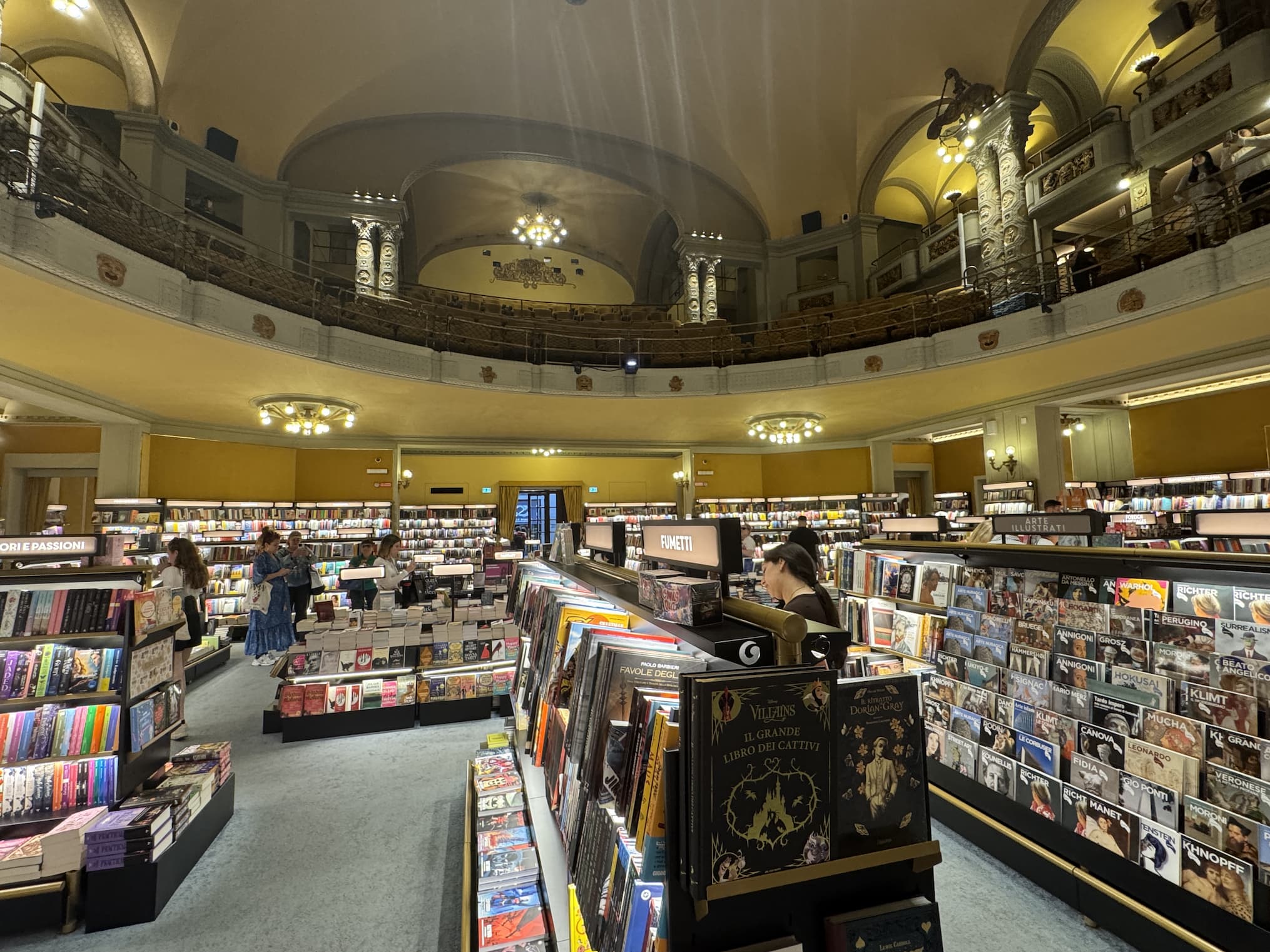 Grand bookstore interior set within an ornate historic space, with soaring arches, balconies, chandeliers, and shelves filled with books. Fearrington Village.