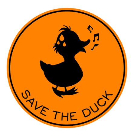 Black silhouette of a singing duck with musical notes, centered inside an orange circular badge with a black border and the words “SAVE THE DUCK” curved along the bottom. Fearrington Village.