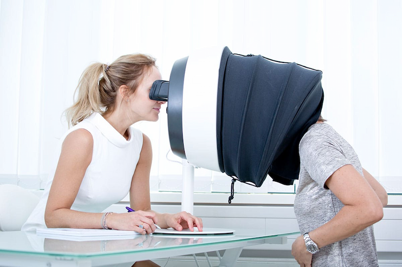 Skincare specialist assisting a client during a facial skin analysis using a professional imaging device to assess skin health and concerns. Fearrington Village.