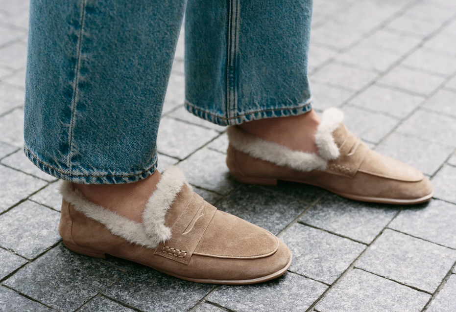 Tan suede loafers with soft cream faux-fur trim, styled with relaxed blue jeans on a stone walkway. Fearrington Village.
