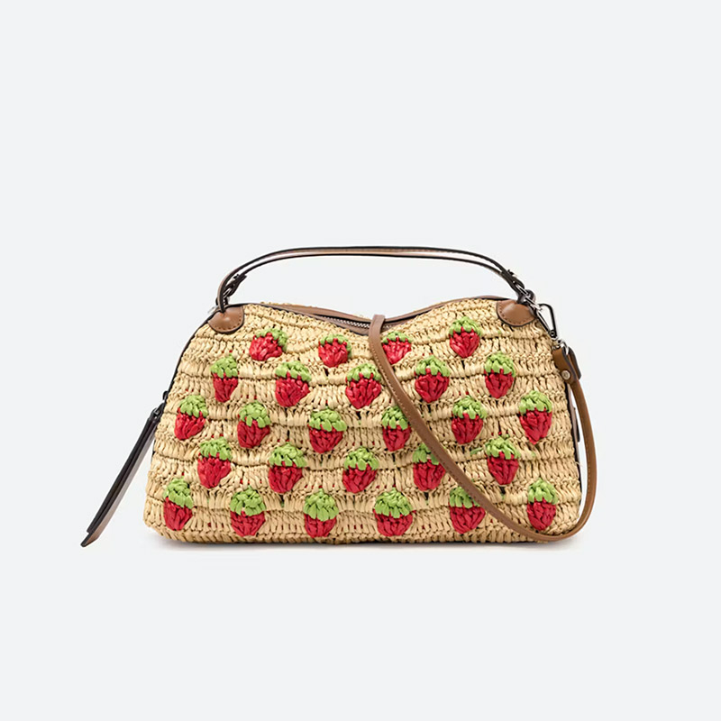Straw handbag decorated with red and green crochet strawberries and finished with brown leather handles and a shoulder strap. Fearrington Village.