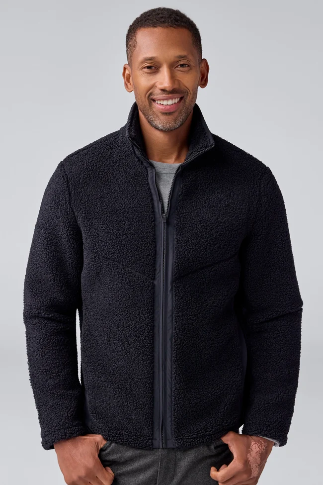Smiling man wearing a black textured zip-up jacket over a gray shirt. Fearrington Village.