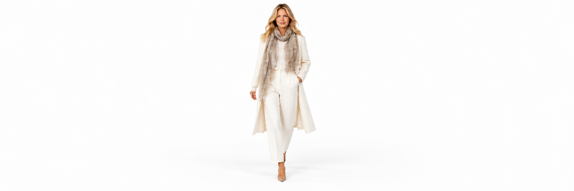 A woman in a cream coat and trousers, walking in a taupe scarf