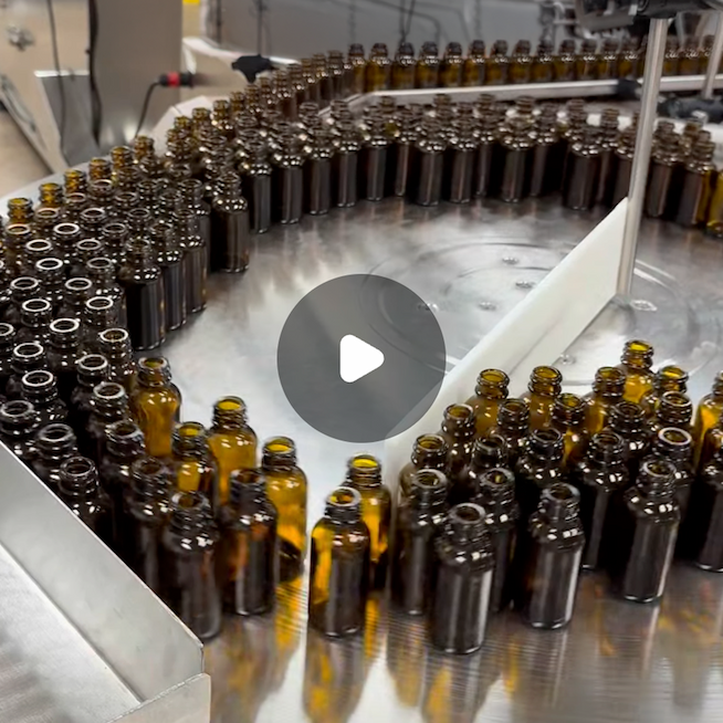 [A screenshot shows a tray of amber glass bottles on an assembly line. Click the image to watch a video of CBDistillery's tinctures being made.]