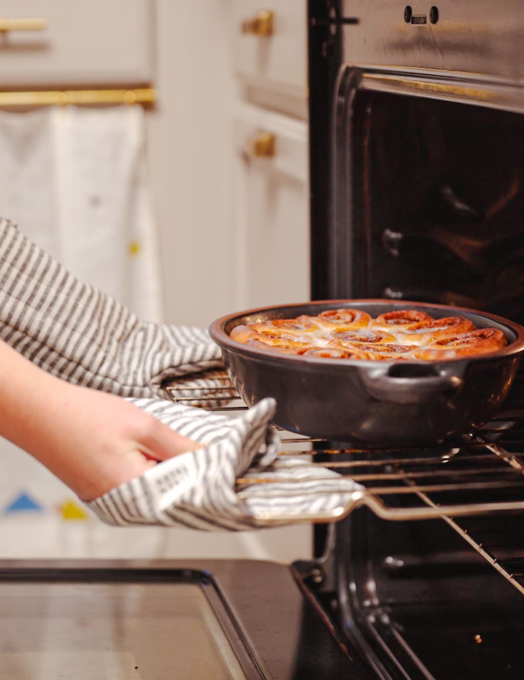 Person sliding a oval baking dish into the oven