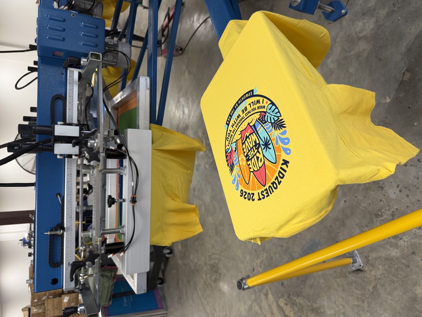 A yellow custom event shirt on our screen-printing press