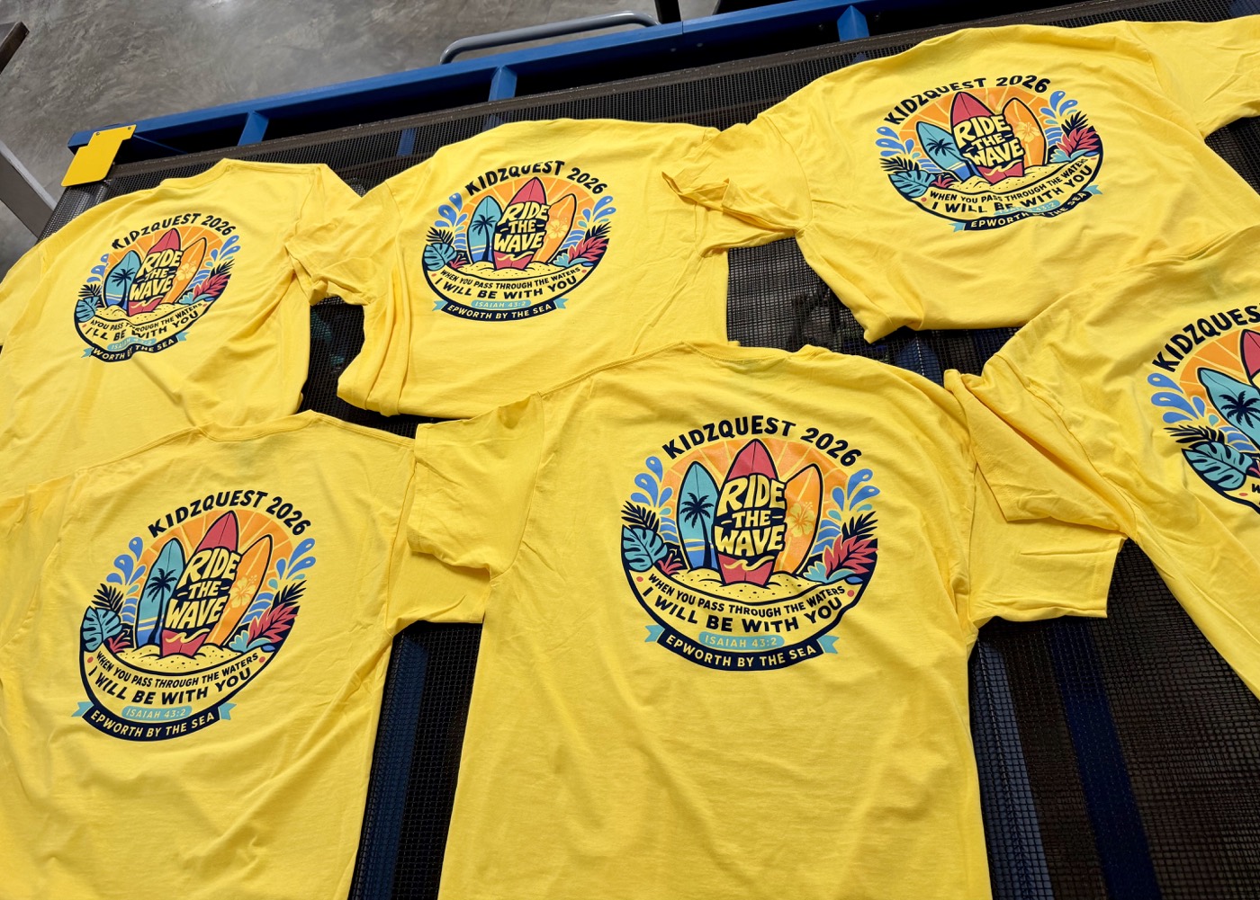Custom yellow Kidzquest event shirts on the print-shop conveyor