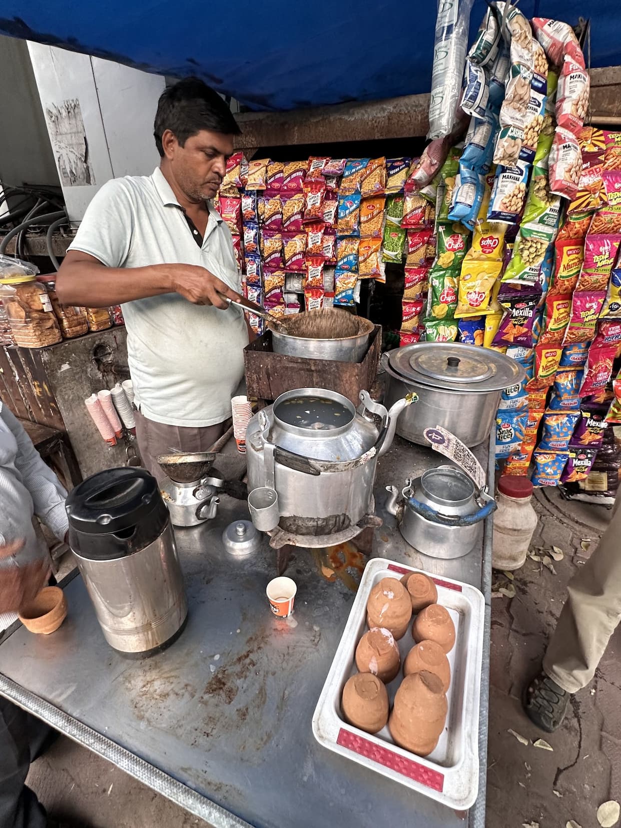 A chai seller at a street stall with a tray of terracotta cups