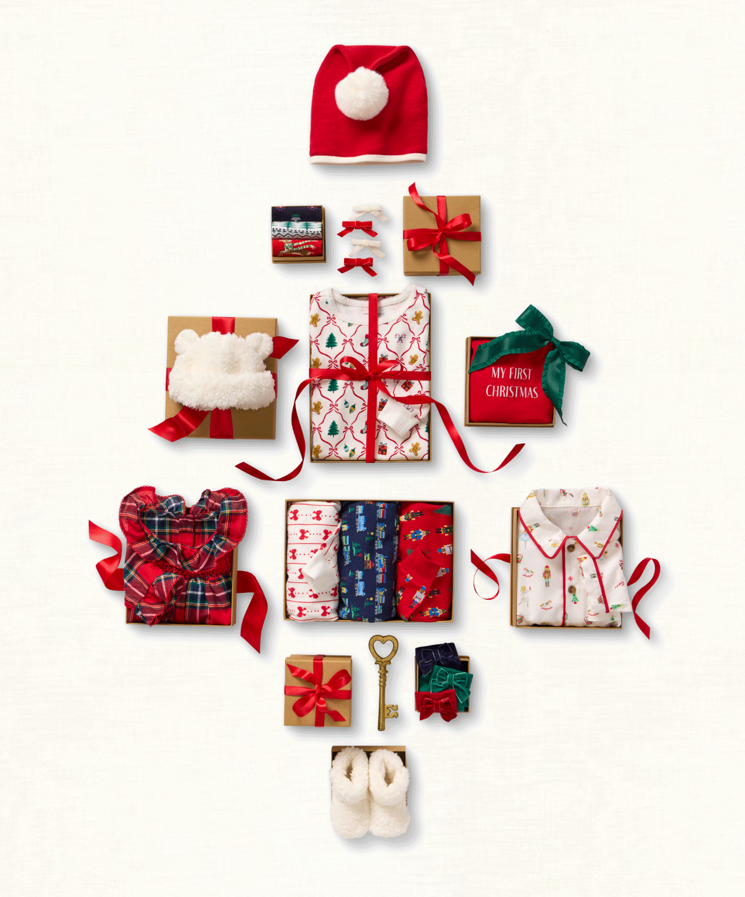 Holiday gift items arranged in a Christmas tree shape including pajamas, a Santa hat, plaid robe, booties, hair bows, and gift boxes - My First Christmas