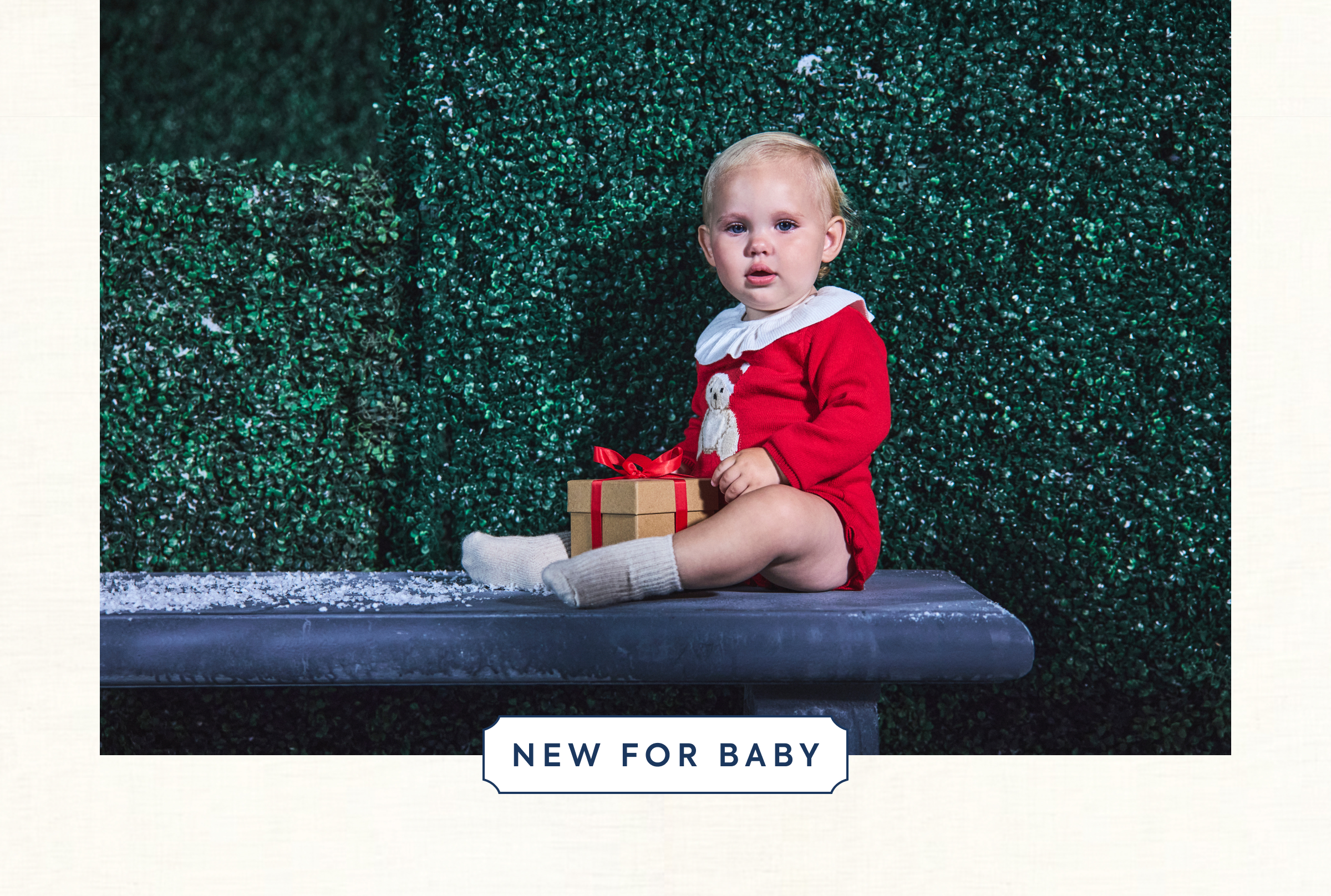 Baby in red Christmas romper holding a gift box on a bench - NEW FOR BABY