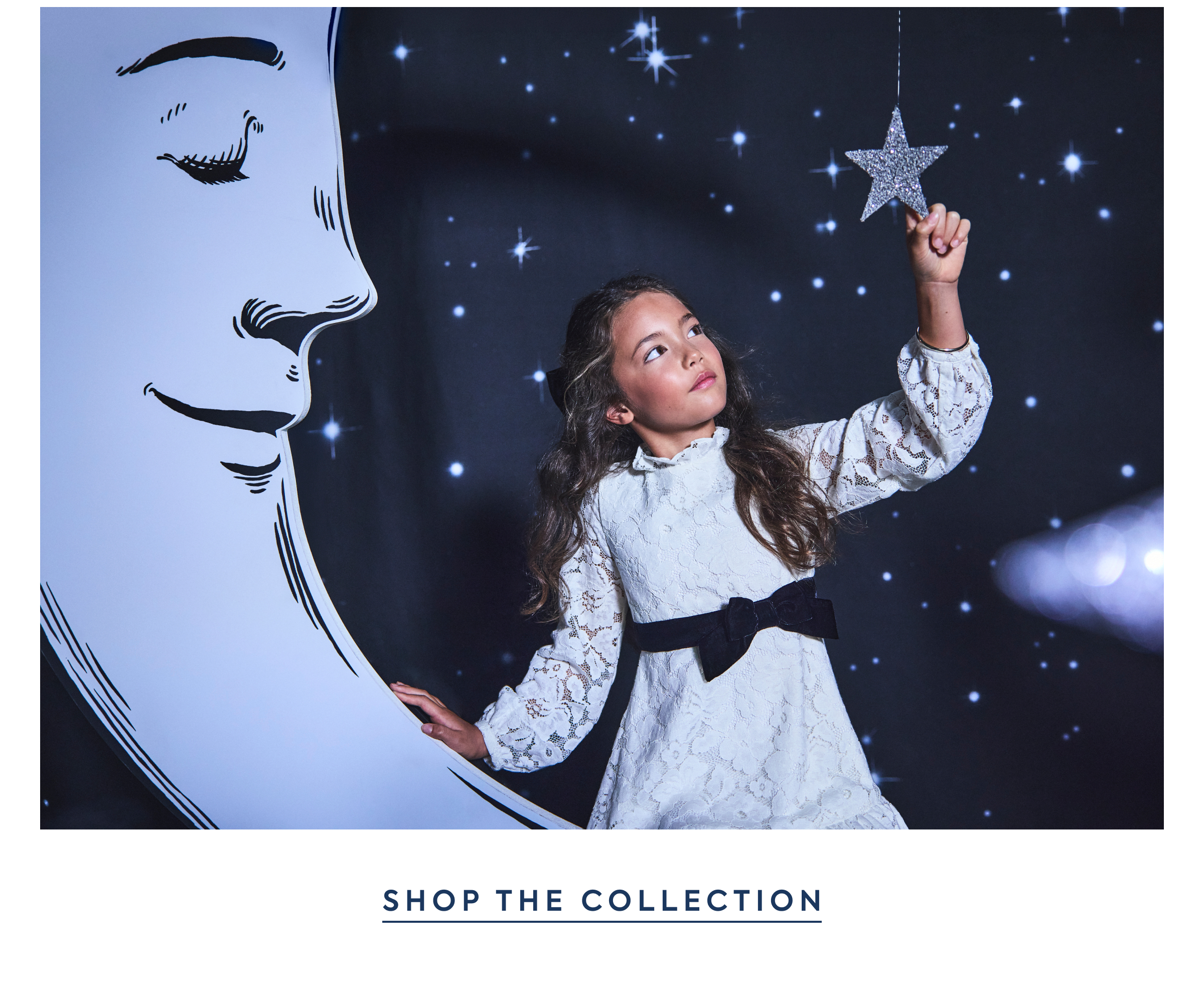 Girl in white lace dress reaching for a glittering star prop against a starry night backdrop with crescent moon illustration - Shop the Collection