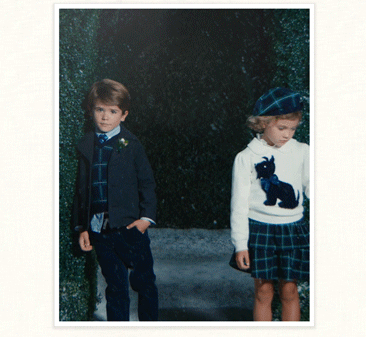 Two children dressed in coordinating navy plaid outfits standing outdoors
