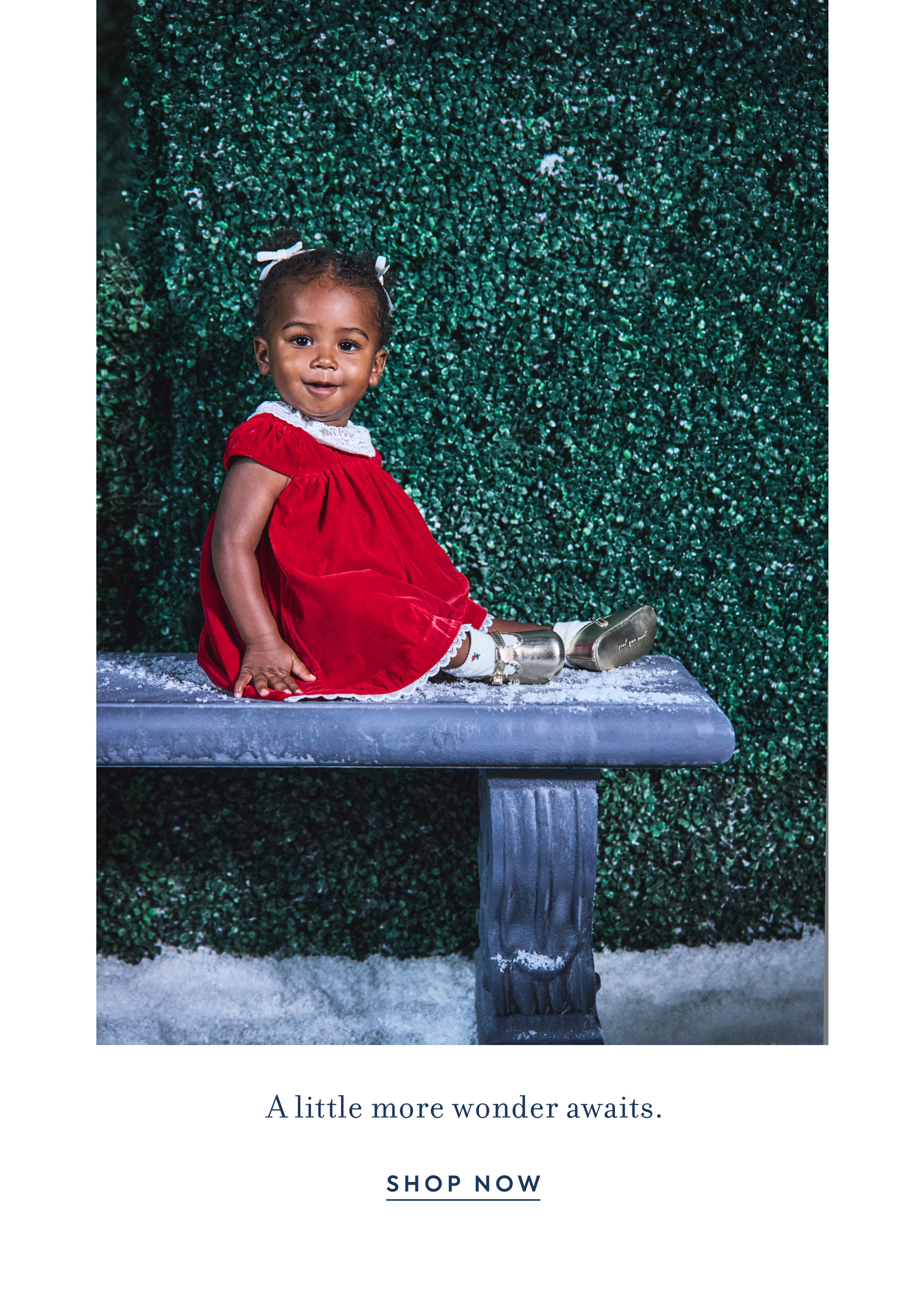 Toddler girl in red velvet dress sitting on snowy bench - A little more wonder awaits. - SHOP NOW