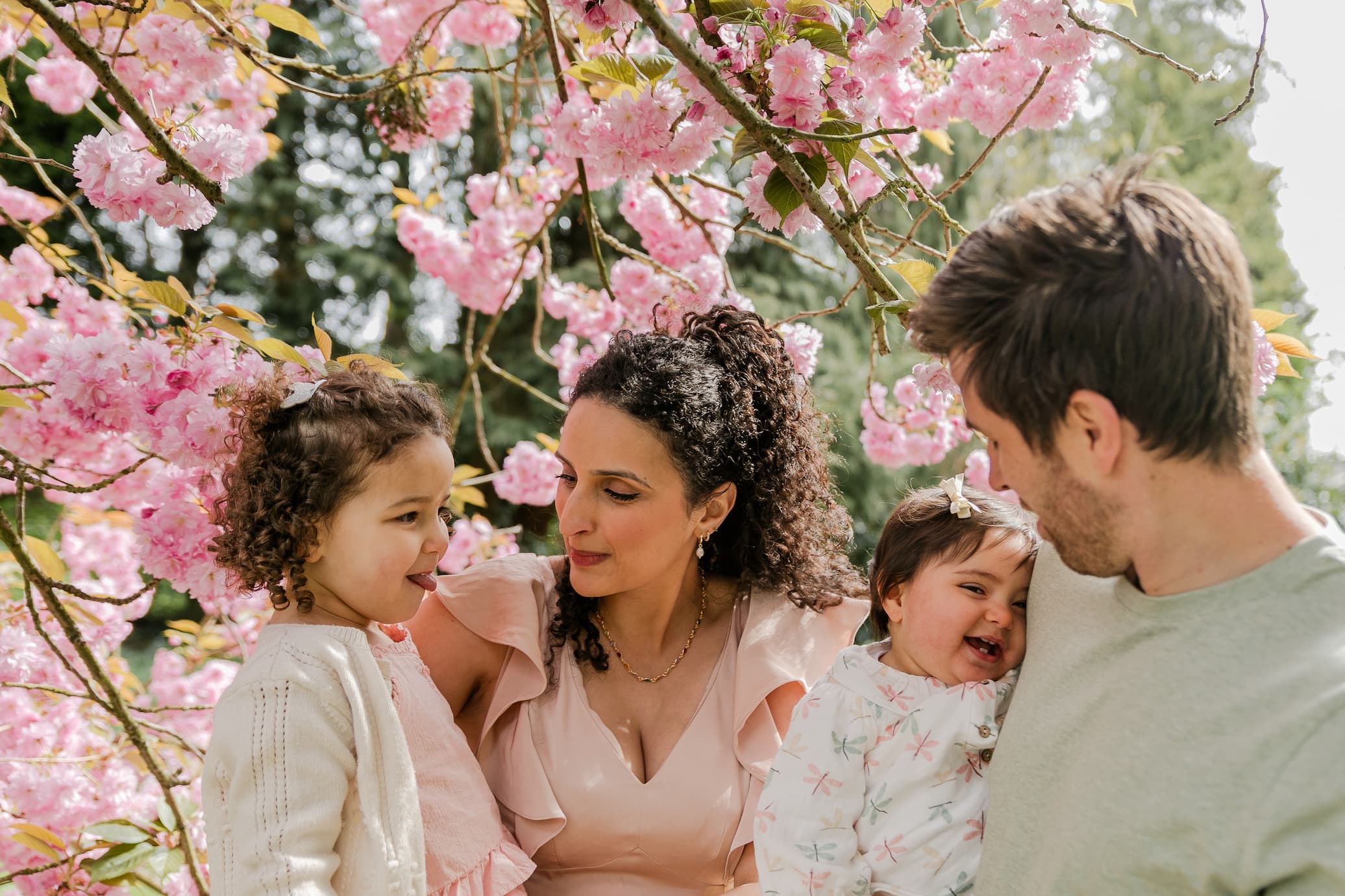 Sabrina and Chris with their two daughters under a cherry blossom tree