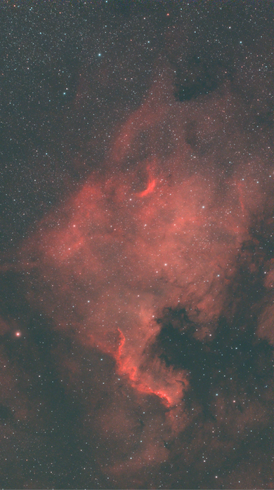 Red glowing nebula clouds threaded with dark dust lanes against a dense field of stars.