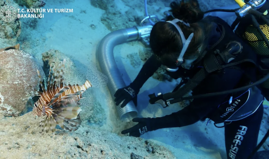 A scuba diver pushes something into a long silver tube.