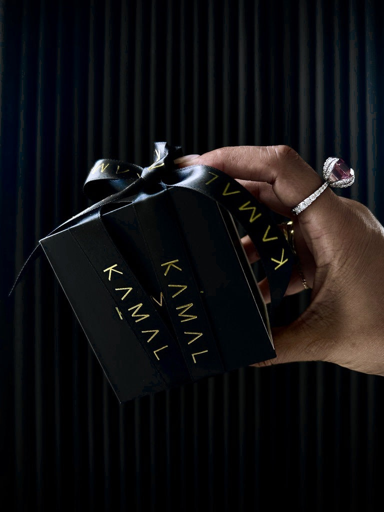 The KAMAL Little Black Box tied with the signature KAMAL ribbon, held out as a gift