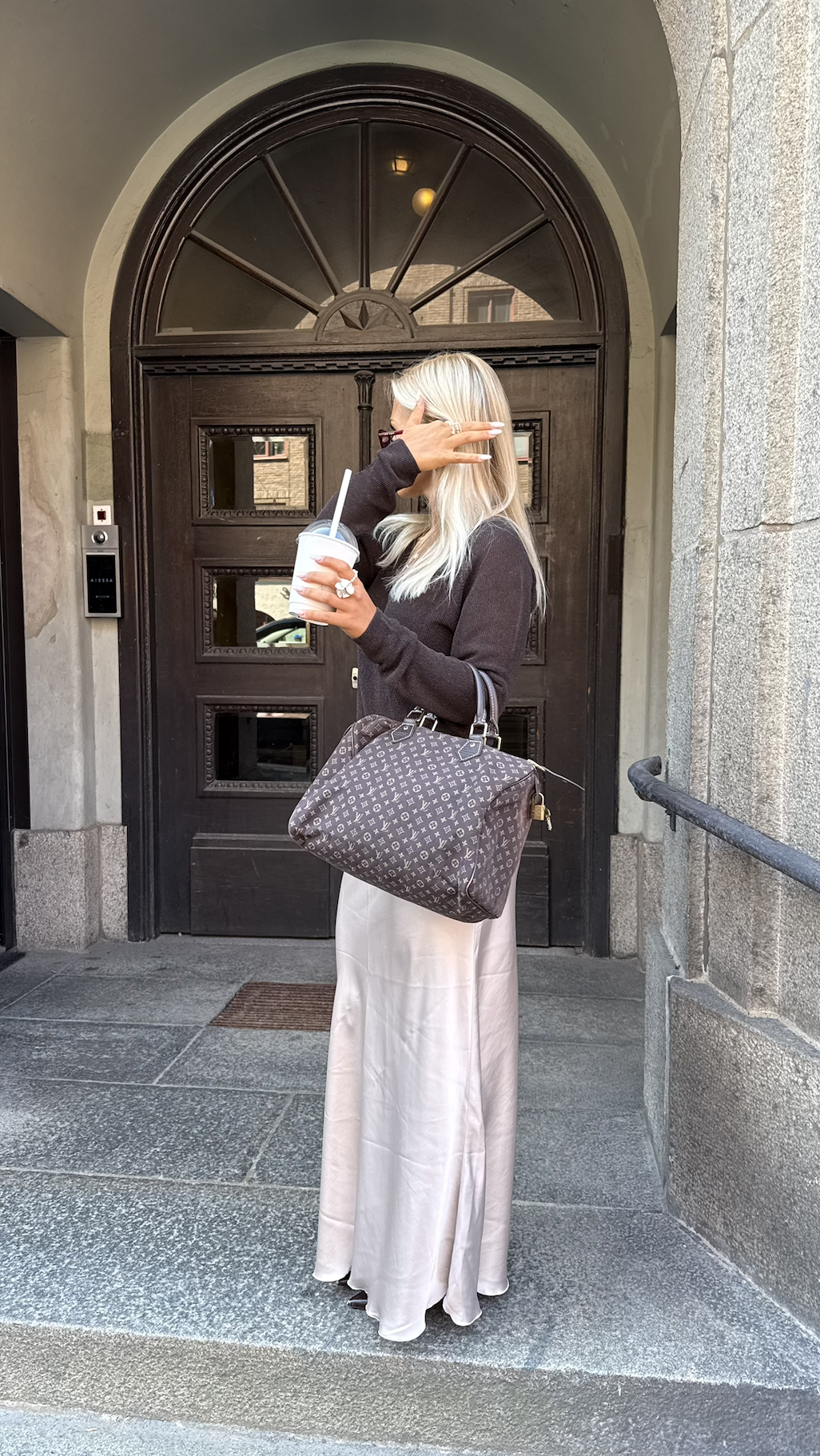 Louis Vuitton handbag styled with a dark top and cream skirt